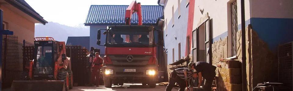 Nákladné auto s hydraulickou rukou a nakladač na dvore predajne v Lendaku